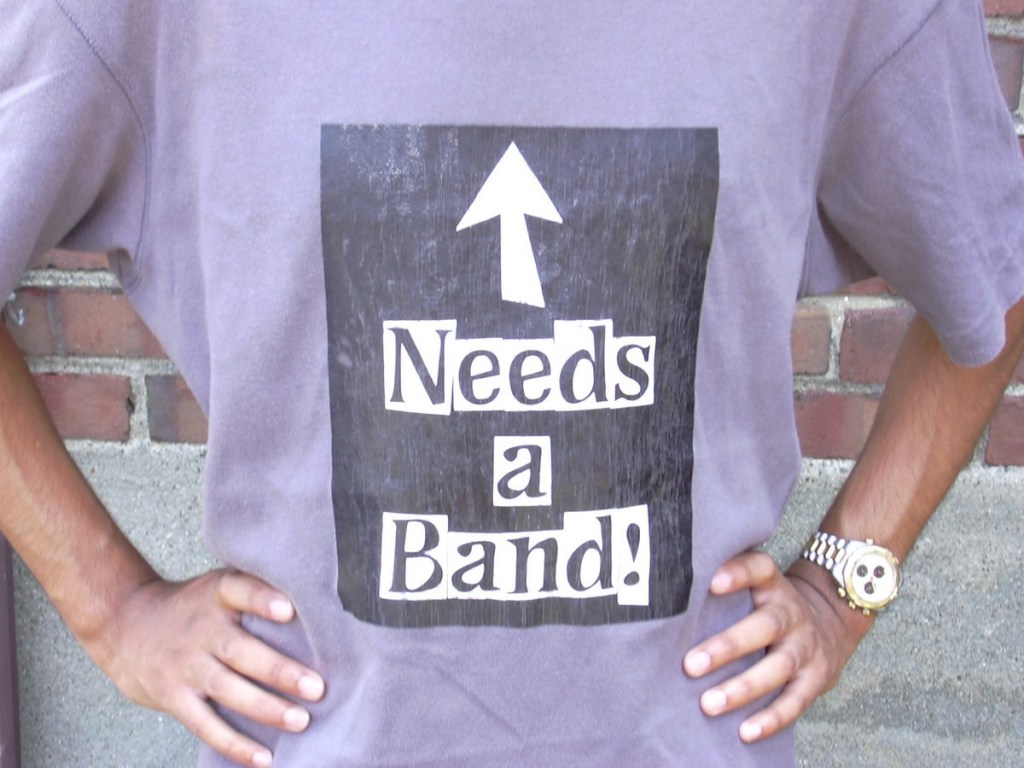 The cover of Needs a Band - a picture of my friend wearing a t-shirt with the title written on it.