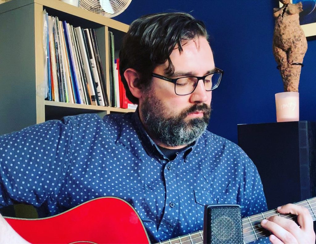 Me playing guitar in front of a microphone